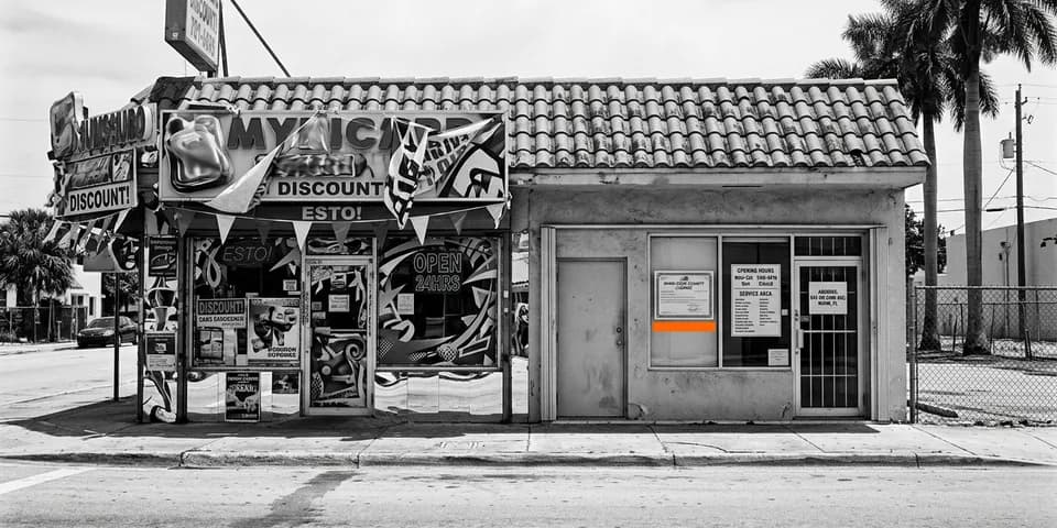 Dos locales de Miami pegados: el de la izquierda sepultado en banderolas y carteles de descuento sin que se sepa a qué se dedica, el de la derecha liso con su licencia de Miami-Dade, el horario y el área de servicio puestos en la ventana bajo una banda naranja Dos locales de Miami pegados: el de la izquierda sepultado en banderolas y carteles de descuento sin que se sepa a qué se dedica, el de la derecha liso con su licencia de Miami-Dade, el horario y el área de servicio puestos en la ventana bajo una banda naranja