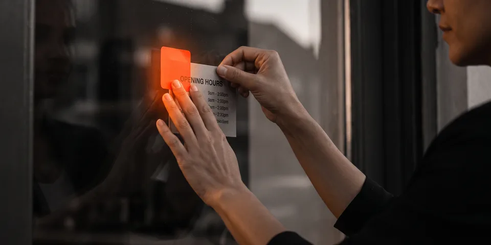 Perfil de Empresa: unas manos colocando la tarjeta de horarios con pegatina naranja Perfil de Empresa: unas manos colocando la tarjeta de horarios con pegatina naranja